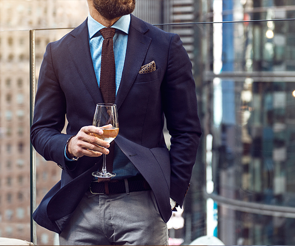 man in suit jacket holding beer glass